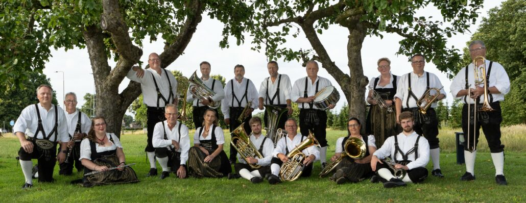 de leden van het orkest staan samen in een park met instrumenten in de hand.